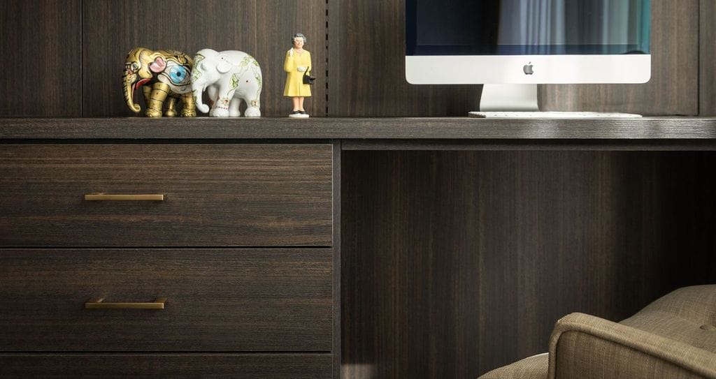 Dark wood finished home office with gold hardware desk drawers and LED lighting created by California Closets
