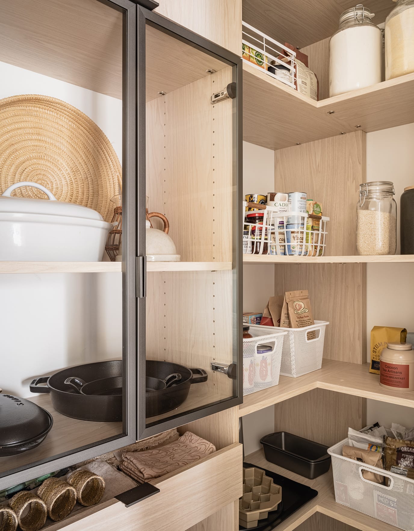 Pantry shelves with glass doors, drawers and corner storage in light wood grain finish by California Closets