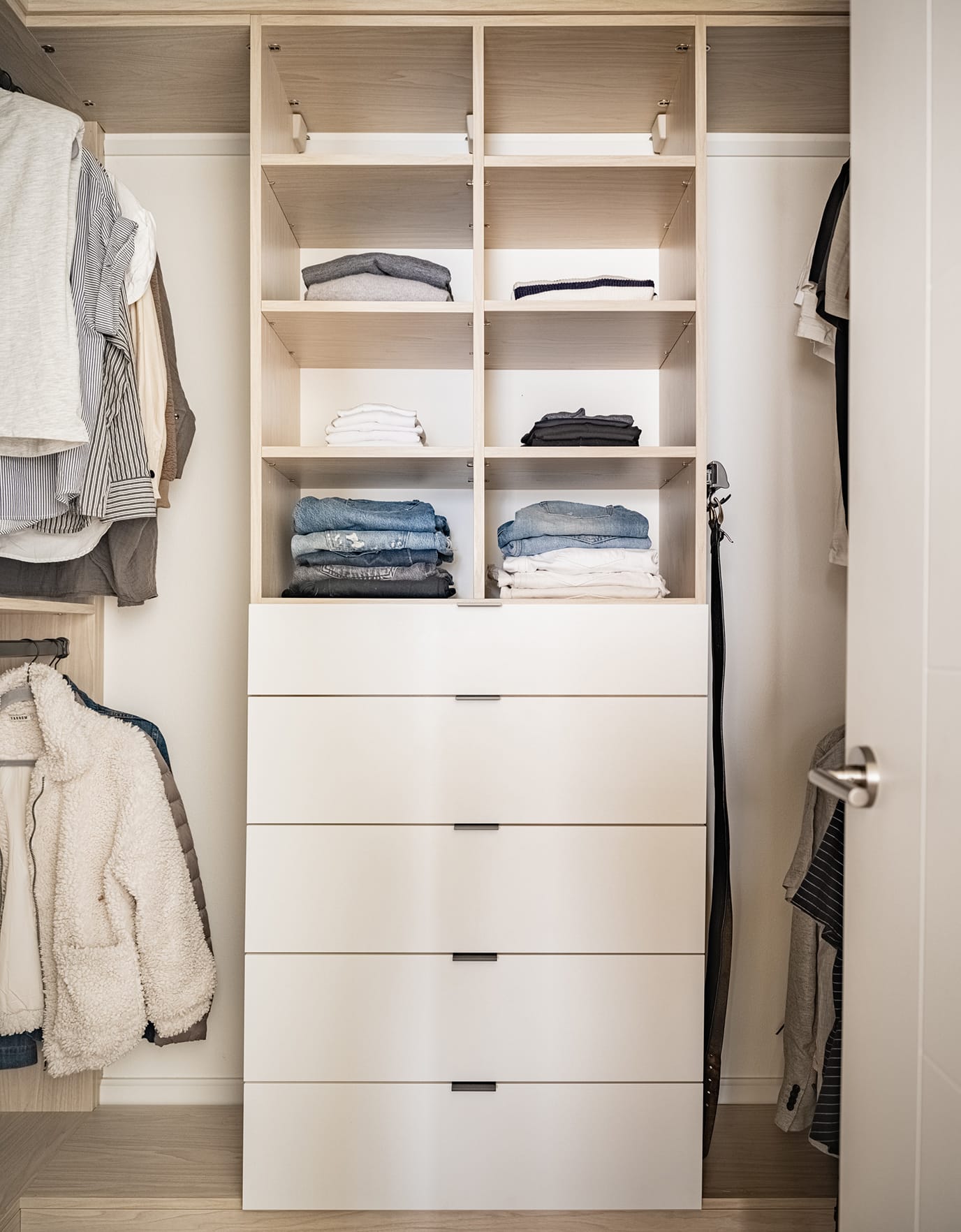 Closet organization in a walk in with custom shelves, drawers and hanging poles for wardrobe created by California Closets
