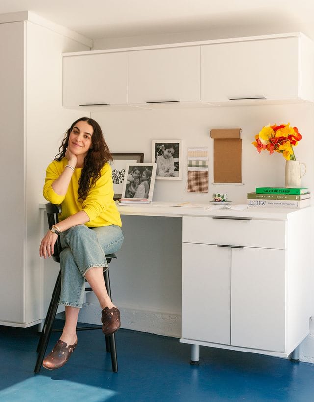 Heather Taylor Home designer sits in her newly designed home office and craft space with additional storage cabinets and built-in desk created by California Closets