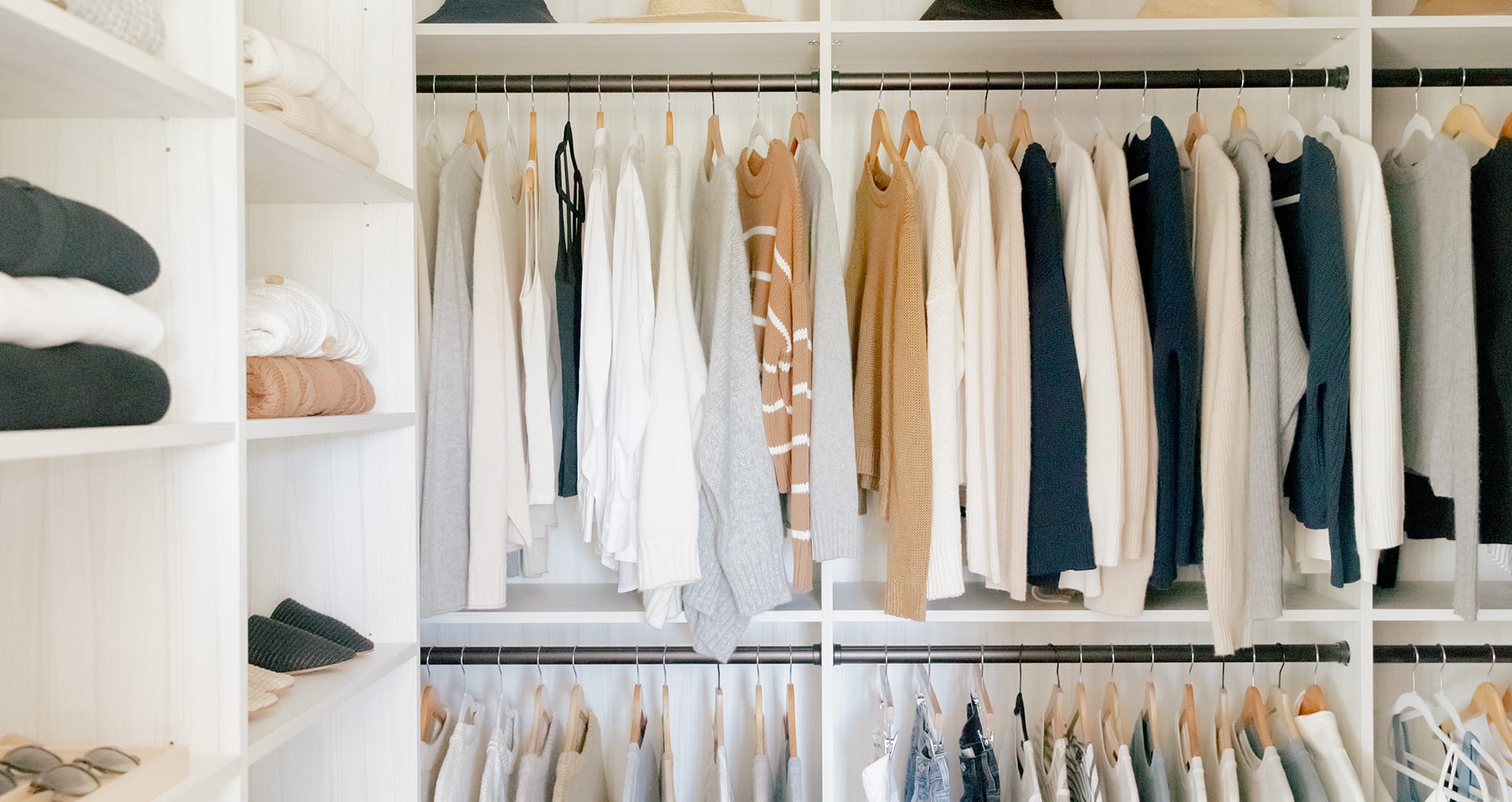 Walk in closet with custom shelving, shoe storage and hanging racks a in neutral wood grain finish by California Closets