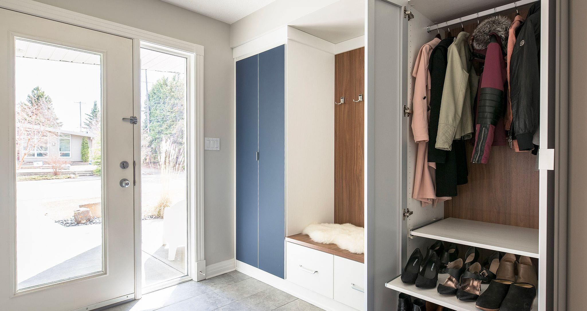 Entryway mudroom storage with shoe shelves and window bench by California Closets