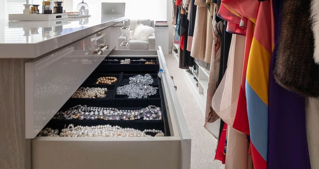 Large walk in closet with islands for jewelry and accessory storage and counter space by California Closets