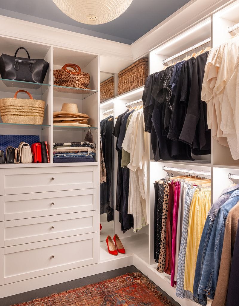 Custom glass shelves, slat drawers, hanging racks and LED lights in a walk in closet designed by California Closets