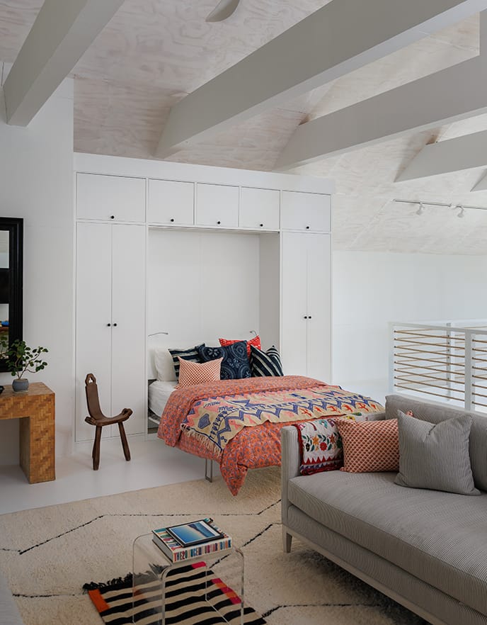 An opened Murphy wall bed show with white wood framing and storage cabinets from California Closets