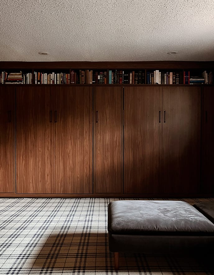 Dark wood finish wall bed designed shown closed with bookshelves above from California Closets