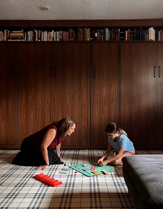 Multipurpose room with hidden wall beds and family shown playing games in customized room from California Closets