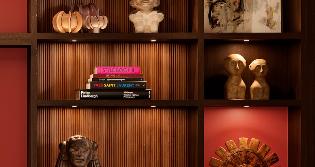 Close-up of bookcase with fluted wood backing, warm lighting, and curated decor by California Closets.