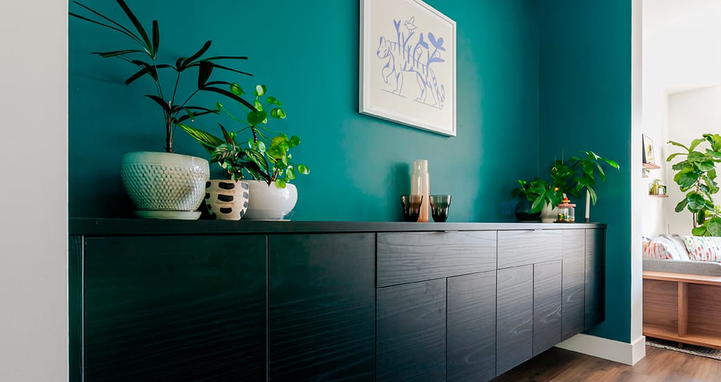 Streamlined home office with black work surface, open cubbies, and task lighting by California Closets.