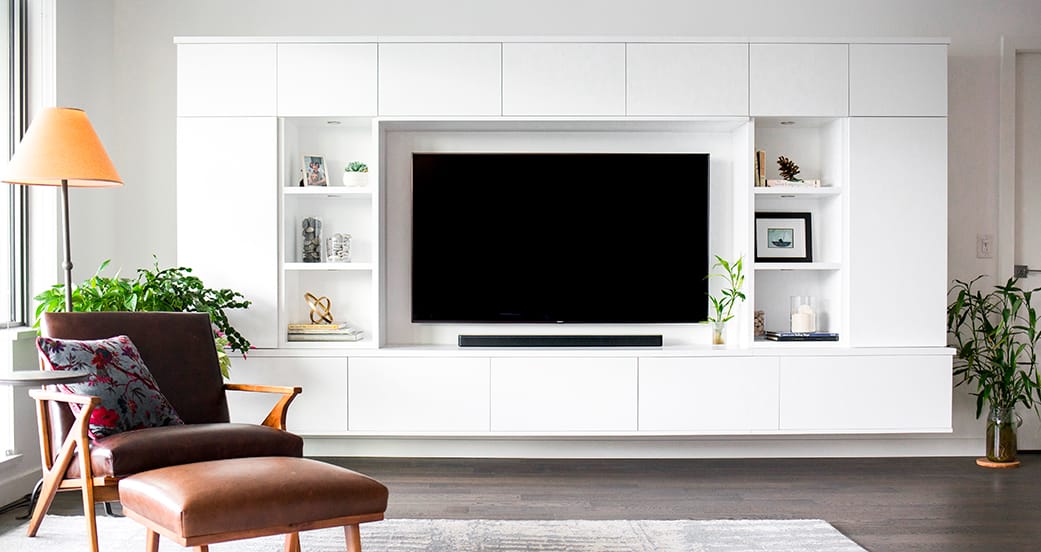 Custom white gloss finish entertainment center with floating shelving designed by California Closets
