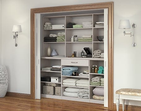 Hallway linens closet in reach in design with custom shelving and utility drawer by California Closets